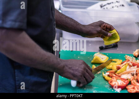 Junge, politischer Flüchtling, entkam aus Afrika mit dem Boot. Dort Anerkennung und Arbeit in Europa. Veganes Restaurant, Koch Auszubildender, raw-Diät, Lieferservice Stockfoto