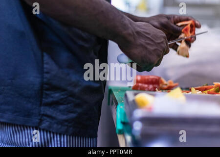 Junge, politischer Flüchtling, entkam aus Afrika mit dem Boot. Dort Anerkennung und Arbeit in Europa. Veganes Restaurant, Koch Auszubildender, raw-Diät, Lieferservice Stockfoto