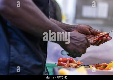 Junge, politischer Flüchtling, entkam aus Afrika mit dem Boot. Dort Anerkennung und Arbeit in Europa. Veganes Restaurant, Koch Auszubildender, raw-Diät, Lieferservice Stockfoto