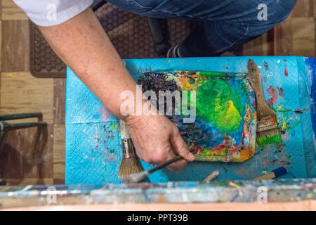 Ein Screen Painter mischt die Farben auf eine Palette. Stockfoto
