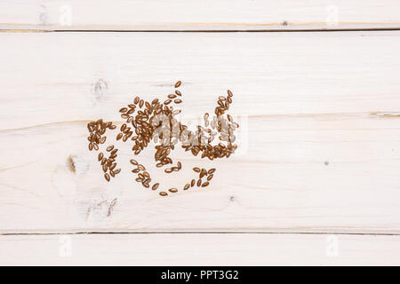 Menge ganze Frische braune flaxseeds flatlay auf weißem Holz Stockfoto