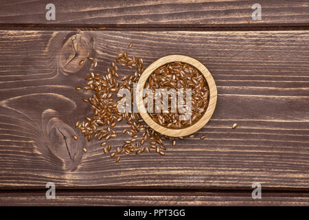 Viele von ganzen frischen braunen Leinsamen mit Houten flatlay auf braunem Holz Stockfoto