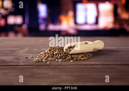 Viele von ganzen frischen braunen Leinsamen mit Holz- Schaufel mit Restaurant im Hintergrund Stockfoto