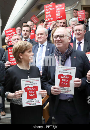 Erster Minister Nicola Sturgeon und Schottland Manager Alex McLeish (rechts), zusammen mit einer Gruppe von MSPs, geholfen, die Zeigt dem Rassismus die rote Karte für die Kampagne "Red Tag" im schottischen Parlament in Edinburgh Verschleiß zu starten. Stockfoto