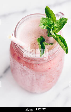 Strawberry rosa Smoothie in einem Glas auf einem weißen Marmor. Im minimalistischen Stil. Blick von oben. Stockfoto