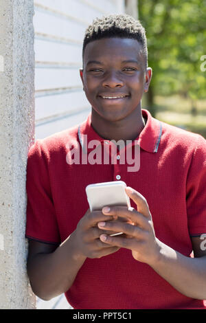 Portrait von Teenager im Freien Sms vom Mobiltelefon Stockfoto