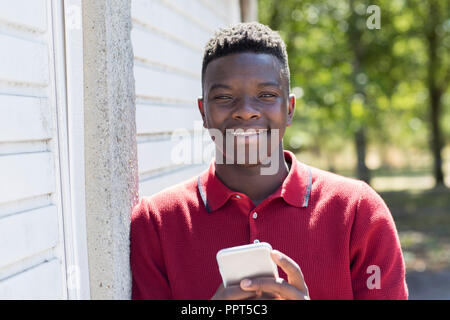 Portrait von Teenager im Freien Sms vom Mobiltelefon Stockfoto