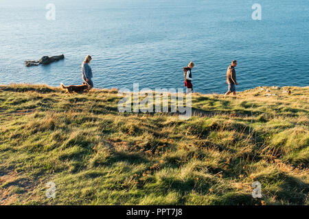 Eine Familie und ihrem Hund genießen Sie einen abendlichen Spaziergang entlang der Küste nach Osten Pentire in Newquay in Cornwall. Stockfoto