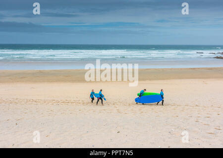 Urlauber, die sich auch für Surfbretter zurück zu Fistral Beach Surf Schule in Newquay in Cornwall. Stockfoto