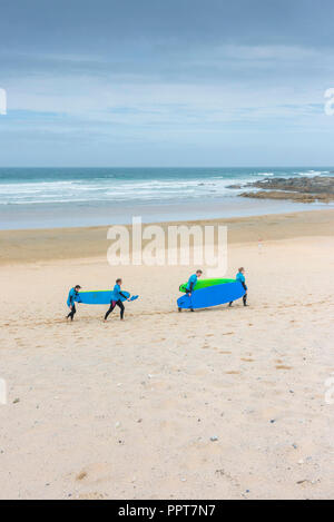 Urlauber, die sich auch für Surfbretter zurück zu Fistral Beach Surf Schule in Newquay in Cornwall. Stockfoto