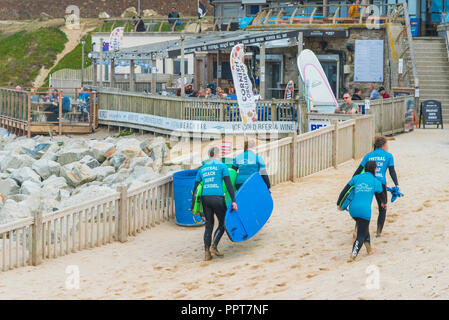 Urlauber, die sich auch für Surfbretter Surfboards zurück zu Fistral Beach Surf Schule in Newquay in Cornwall. Stockfoto