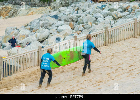 Zwei Urlauber ihre Surfbretter gemietet Zurück zu Fistral Beach Surf Schule in Newquay in Cornwall. Stockfoto