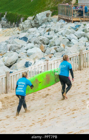 Zwei Urlauber ihre Surfbretter gemietet Zurück zu Fistral Beach Surf Schule in Newquay in Cornwall. Stockfoto