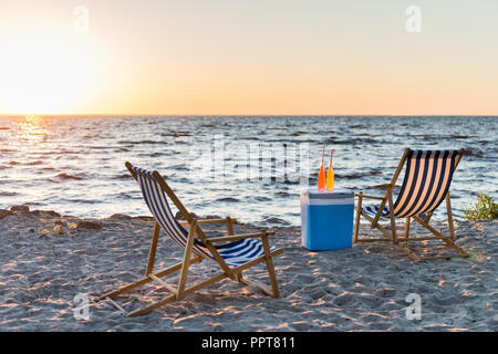 Sommer Getränke auf Kühler und Liegestühlen am Strand bei Sonnenuntergang Stockfoto