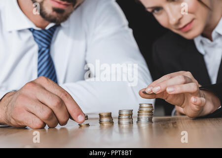 Zugeschnittenes Bild von Unternehmensberatern stapeln Münzen auf den Tisch im Büro Stockfoto