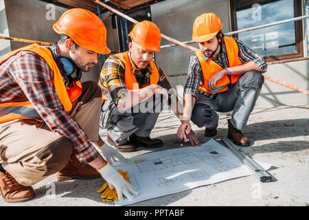 Nahaufnahme der Gruppe von Bauherren in Gespräch über Gebäude planen Stockfoto