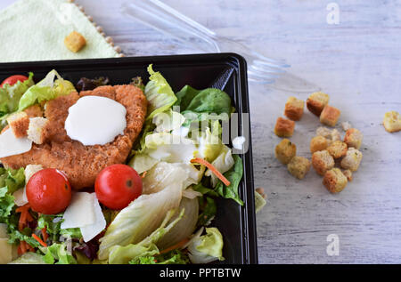 Close up Caesar Salat mit hausgemachten Croutons, Hühnerfleisch, Parmesan und Caesar Dressing in großen schwarzen Platte Stockfoto