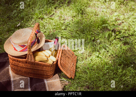 Korb für Picknick mit Bananen und einer Flasche Wein im Park Stockfoto