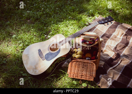 Korb für Picknick mit Bananen und Akustikgitarre in Park Stockfoto