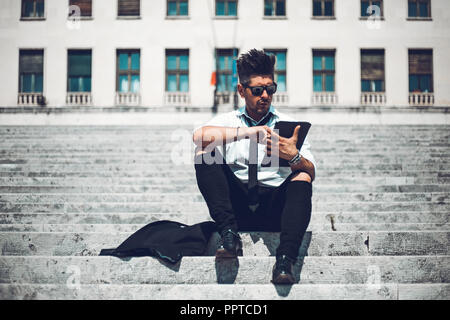Gerne modische lächelnde junge Unternehmer beobachten und Arbeiten am Laptop außerhalb des Büros. Stockfoto