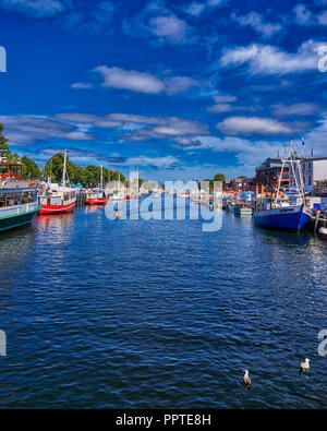 Bunte Fischerboote im ruhigen Kanal ruht auf diesen Frühling heißen Tag in Warnemünde, Rostock, Mecklenburg, Deutschland. Stockfoto