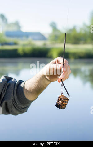 Hand ein Angler hält eine groundbait Box mit einem Köder. Stockfoto