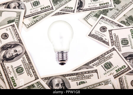 Stapel von Dollar Banknoten mit Glühbirne auf weißem Hintergrund. Stockfoto