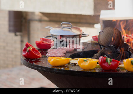 Fleisch, Steaks und Würstchen mit Gemüse kochen auf Grill und glühende Kohlen. Barbecue auf der Außenseite Picknick im Sommer. Stockfoto