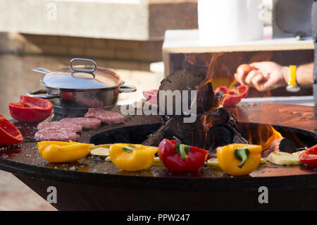 Fleisch, Steaks und Würstchen mit Gemüse kochen auf Grill und glühende Kohlen. Barbecue auf der Außenseite Picknick im Sommer. Stockfoto