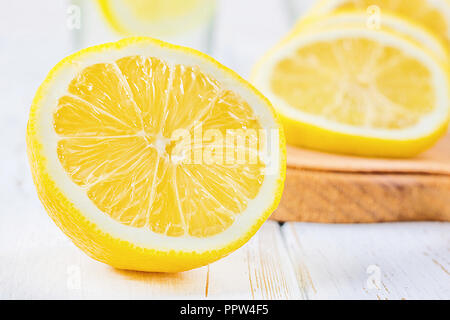 Ein Becherglas und einen Krug kalten Limonade auf einem weißen Hintergrund Holz umgeben von Zitronen Stockfoto