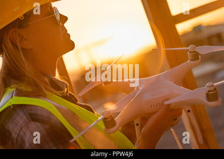 Weibliche Unmanned Aircraft Systems (UAS) Quadcopter Drone Pilot Holding Drohne an der Baustelle. Stockfoto