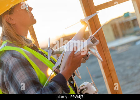 Weibliche Unmanned Aircraft Systems (UAS) Quadcopter Drone Pilot Holding Drohne an der Baustelle. Stockfoto