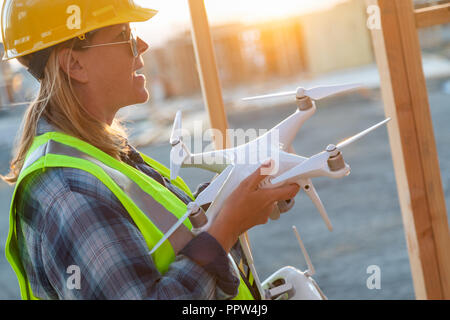 Weibliche Unmanned Aircraft Systems (UAS) Quadcopter Drone Pilot Holding Drohne an der Baustelle. Stockfoto