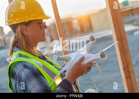 Weibliche Unmanned Aircraft Systems (UAS) Quadcopter Drone Pilot Holding Drohne an der Baustelle. Stockfoto