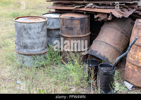 Alte Fässer für Diesel. Metallbehälter für Öl auf dem Schrottplatz. Jahreszeit der Herbst. Stockfoto