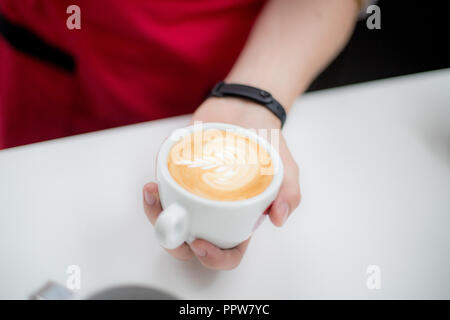 Barista hält eine Tasse mit einem figurativen Kaffee Latte in Form eines Apple Stockfoto
