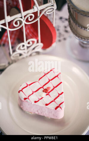 Erdbeerkuchen in der Form eines Herzens, das auf einem weissen Teller, auf dem Tisch im Cafe. Stockfoto