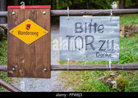 Gelbe Schweizer Schild mit der Aufschrift Fußweg in deutscher Sprache. Ein Mann aus dem Zeichen fragt Menschen freundlich die Tür zu schließen beim Eingeben. Stockfoto