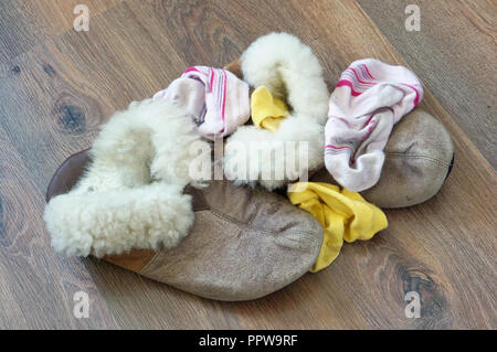 Das alte Fell Frauen Haus Hausschuhe und Socken liegen ein Haufen auf dem Holzboden Stockfoto