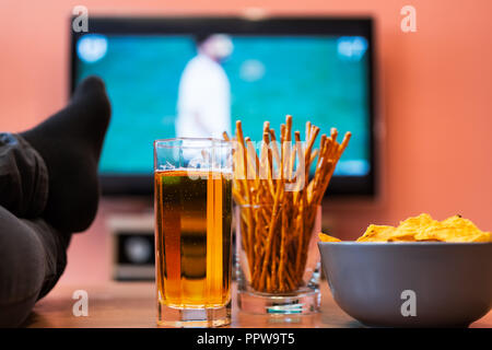 Beobachten Fußball oder Fußball im Fernsehen mit Bier, Chips und Grissini. Stockfoto