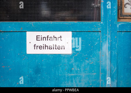 Weißes Verkehrsschild gegen eine blaue Tür in der Stadt Thun (Berner Oberland, Schweiz), die Ausfahrt frei zu halten. Stockfoto