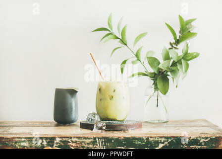 Iced Matcha Latte mit Milch giessen von Krug, horizontale Zusammensetzung Stockfoto