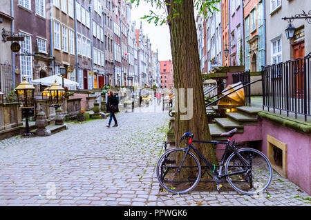 Danzig, Pommern, Polen: ein Fahrrad lehnt an einem Baum als Menschen Spaziergänge an der St. Mary's Street (ul. Mariacka) im Herzen der Altstadt. Stockfoto