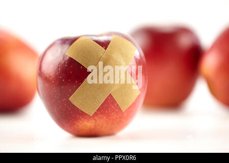 Red Apple mit Bandage auf weißem Hintergrund. Stockfoto