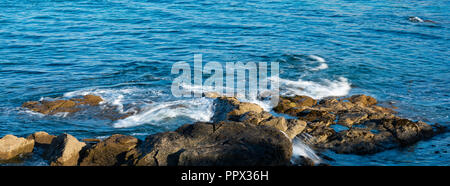 Wellen über die Felsen in der Nähe von Porthmeor Beach St. Ives brechen Stockfoto