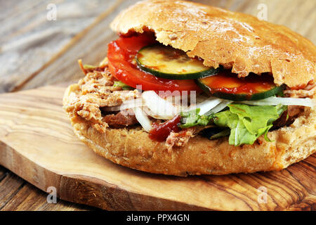 Gezogene Schweinefleischsandwiche mit BBQ Sauce, Kohl und Gurken auf hölzernen Tisch. Stockfoto