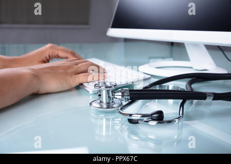 In der Nähe von einem Arzt Hand mit Computer über Schreibtisch Stockfoto