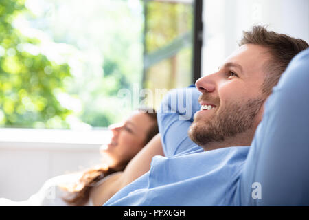 Lächelnde junge Paar entspannten Sitzen auf der Couch zu Hause Stockfoto