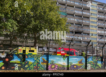 Notdienste Fahrzeuge mit einem Basketballplatz, die nach einem Brand in einem der beiden Blöcke im Elsass Wendover Road Aylesbury Immobilien, Southwark SE17 geparkt, am 24. September 2018 in London, England. Teil einer auf 2 Ebenen flach auf dem vierten und fünften Stock des 15-stöckigen Block beschädigt wurde. Eine Frau und zwei Kinder verlassen das Haus, bevor die Feuerwehr eingetroffen. Sie wurden an der Szene für Rauch einatmen von London Ambulance Service Crew behandelt und zu Krankenhaus gebracht. Ein anderer Mann war auch bei der Szene mit Rauchvergiftungen behandelt. Stockfoto