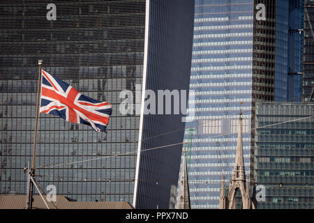 Vom Südufer der Themse, ein Union Jack Flagge auf dem Bug von WW2 Schlachtschiff HMS Belfast mit der Stadt London Fliegen gesehen - finanzielle Zentrum der Hauptstadt (aka der Square Mile) im Hintergrund, am 27. September 2018 in London, England. Stockfoto